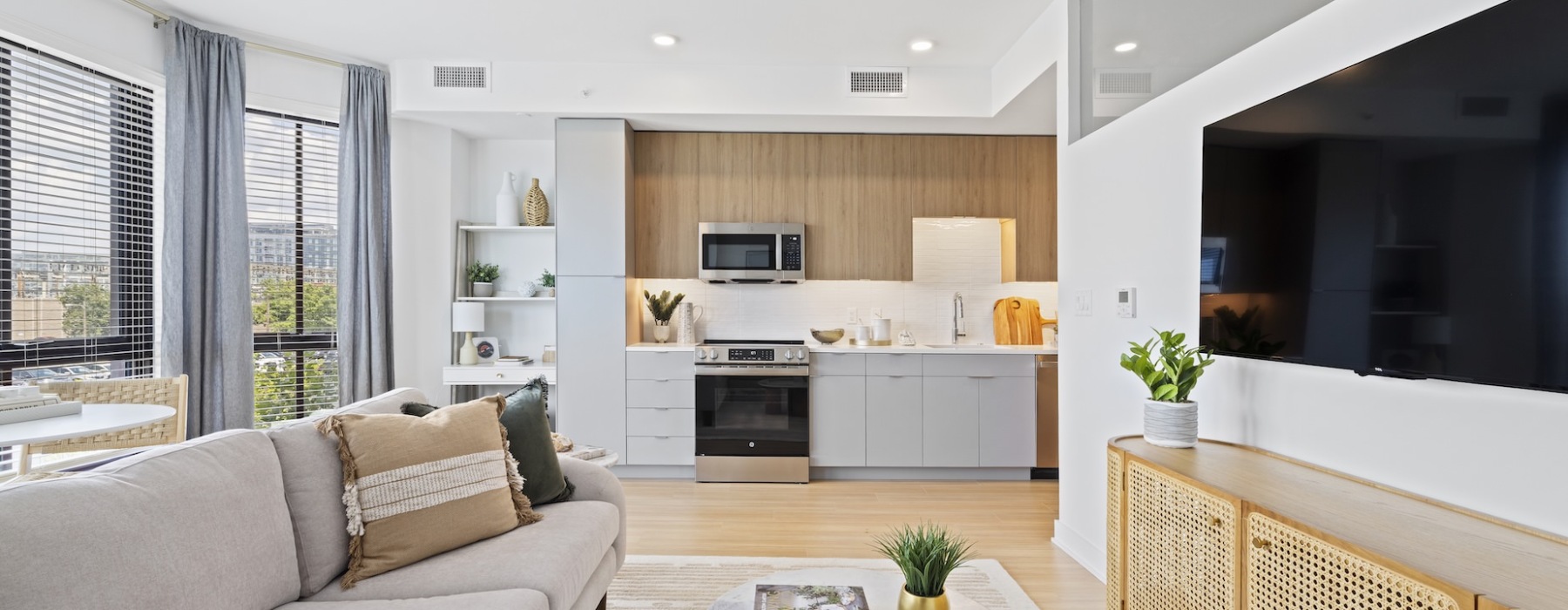 Bright open living room with floor to ceiling windows and views of the kitchen