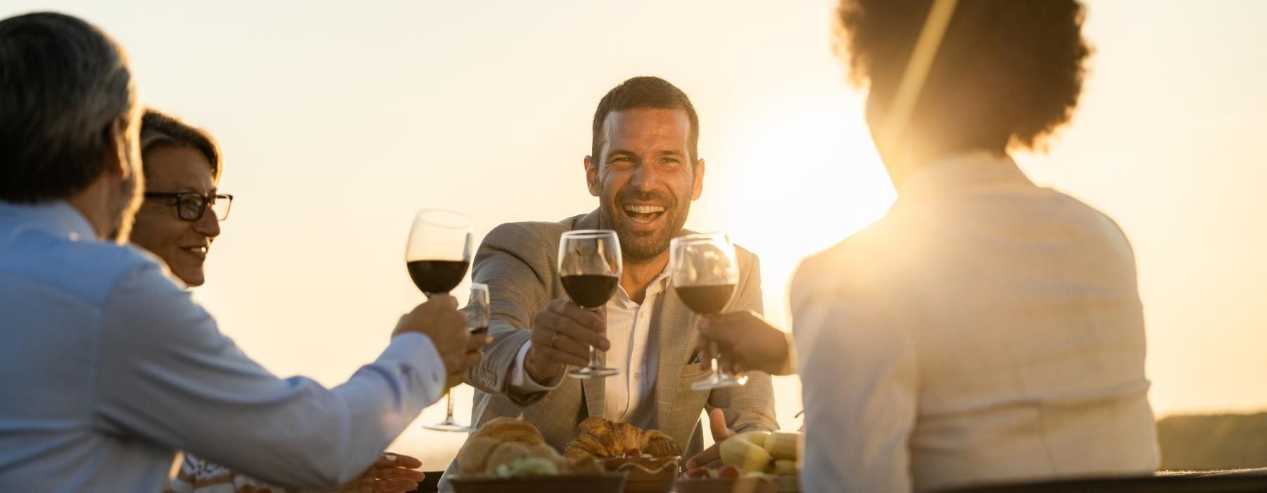 a group of people sitting at a table with food and drinks